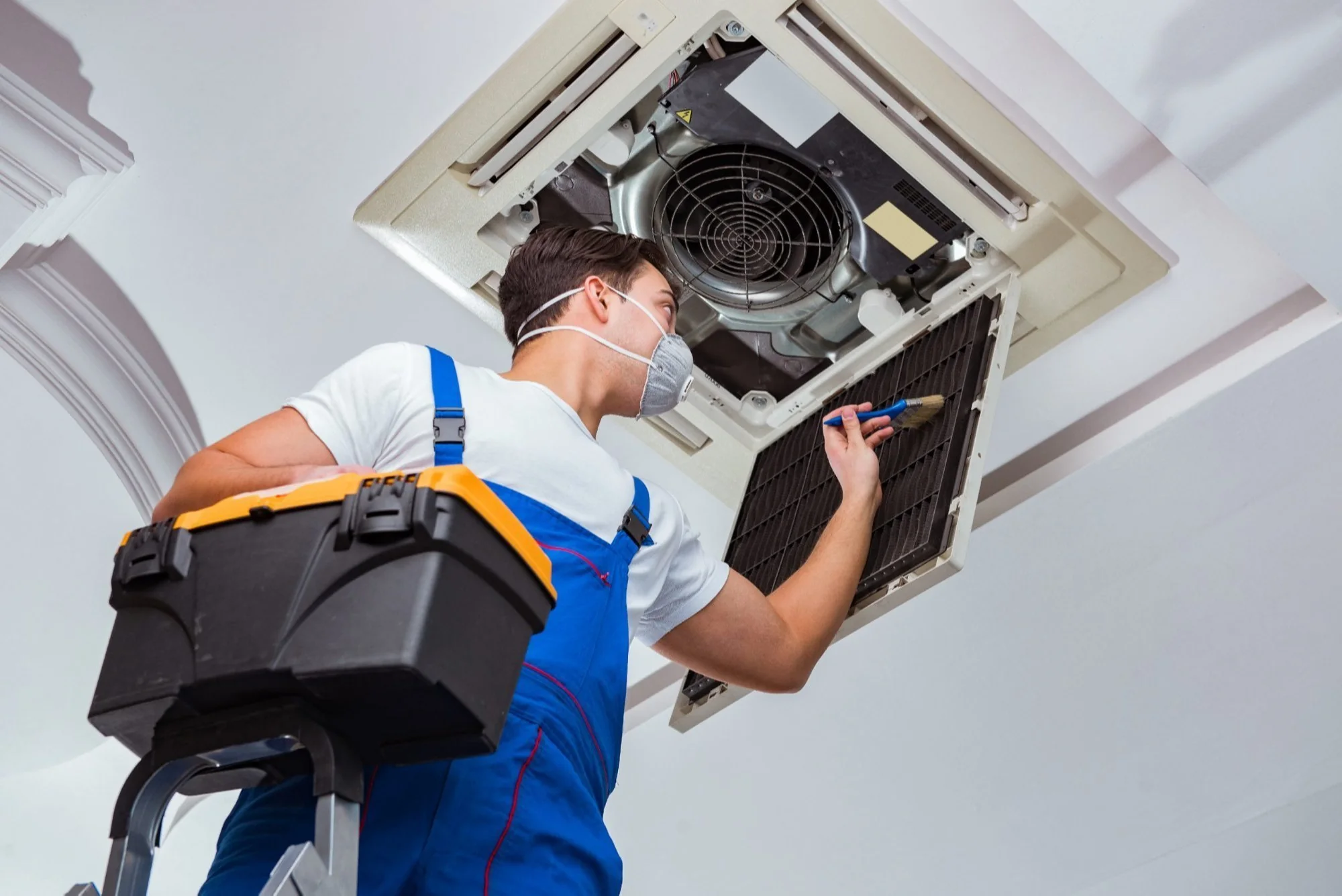 HVAC technician servicing a ceiling-mounted residential air conditioning unit
