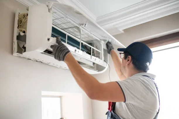 Technician opening and cleaning an indoor air conditioning unit to support cleaner airflow