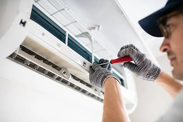 Technician checking the interior of a wall-mounted air conditioning unit for airflow concerns