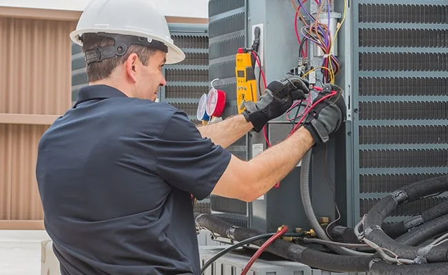 HVAC technician diagnosing outdoor air conditioning equipment with electrical test tools