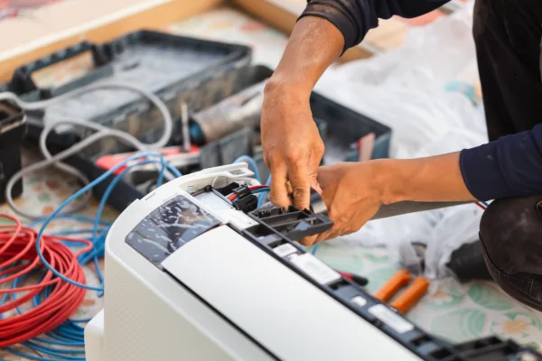 Technician connecting wiring and components during residential HVAC equipment replacement